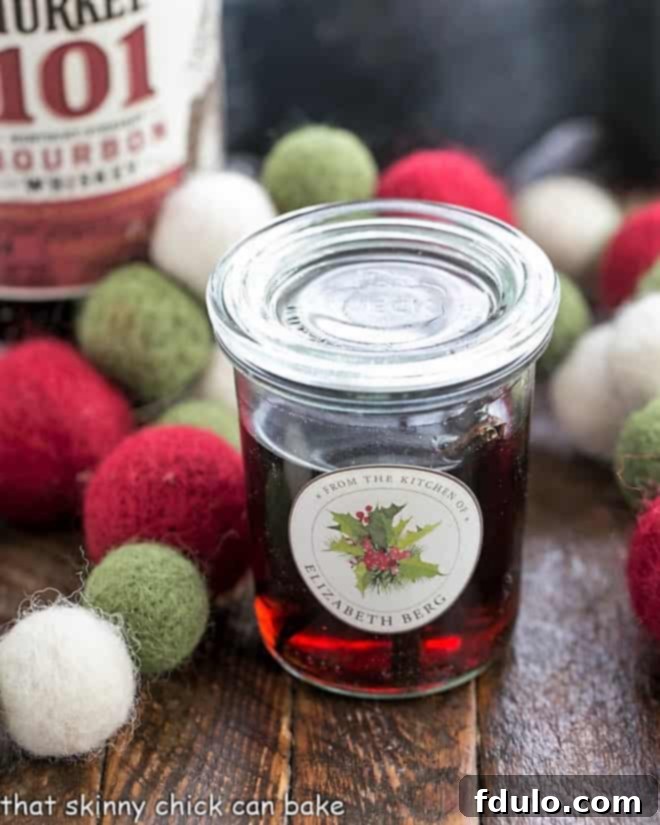 Homemade Vanilla Extract - Only 2 ingredients and time make for a fabulous holiday or hostess gift! Homemade Vanilla Extract in a decorative jar for gifting, adorned with a festive ribbon.