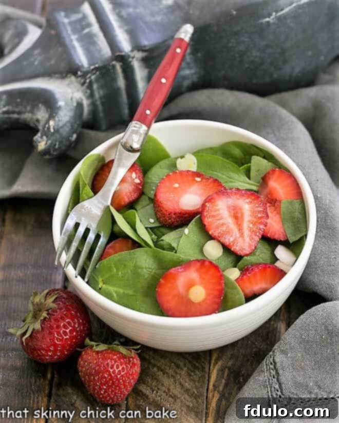 Strawberry spinach salad in a salad bowl with a red handled fork