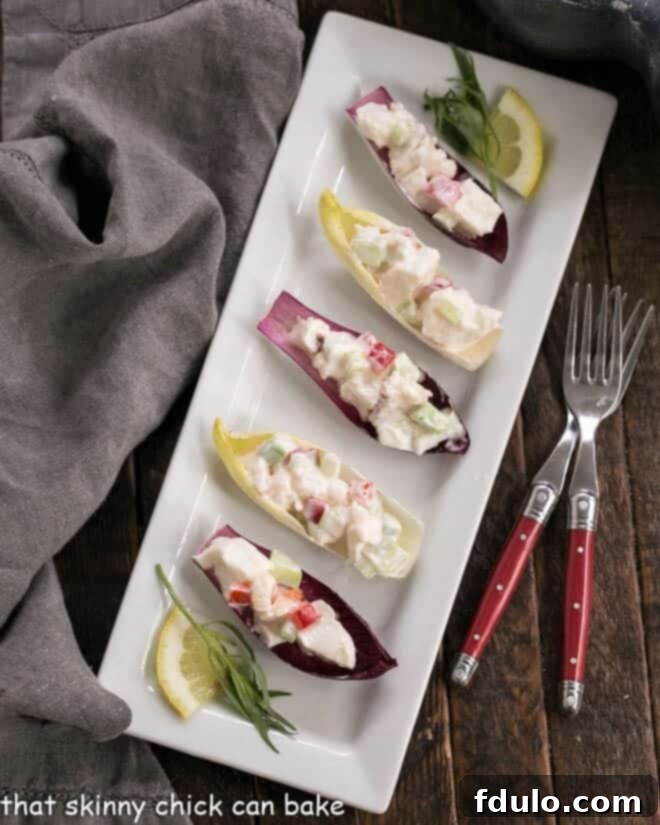An inviting overhead shot of Lobster Salad in Endive Cups, elegantly arranged on a sleek white rectangular tray, highlighting the exquisite simplicity and appealing freshness of the dish, ready for guests.