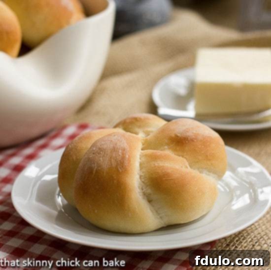 A perfectly baked, golden-brown Moomie's Bun resting on a small white plate, showcasing its soft texture and inviting crust.