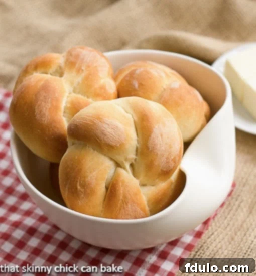 A cluster of golden-brown Moomie's Buns nestled in a white ceramic bowl, placed on a classic red-and-white checked napkin, highlighting their inviting appeal.