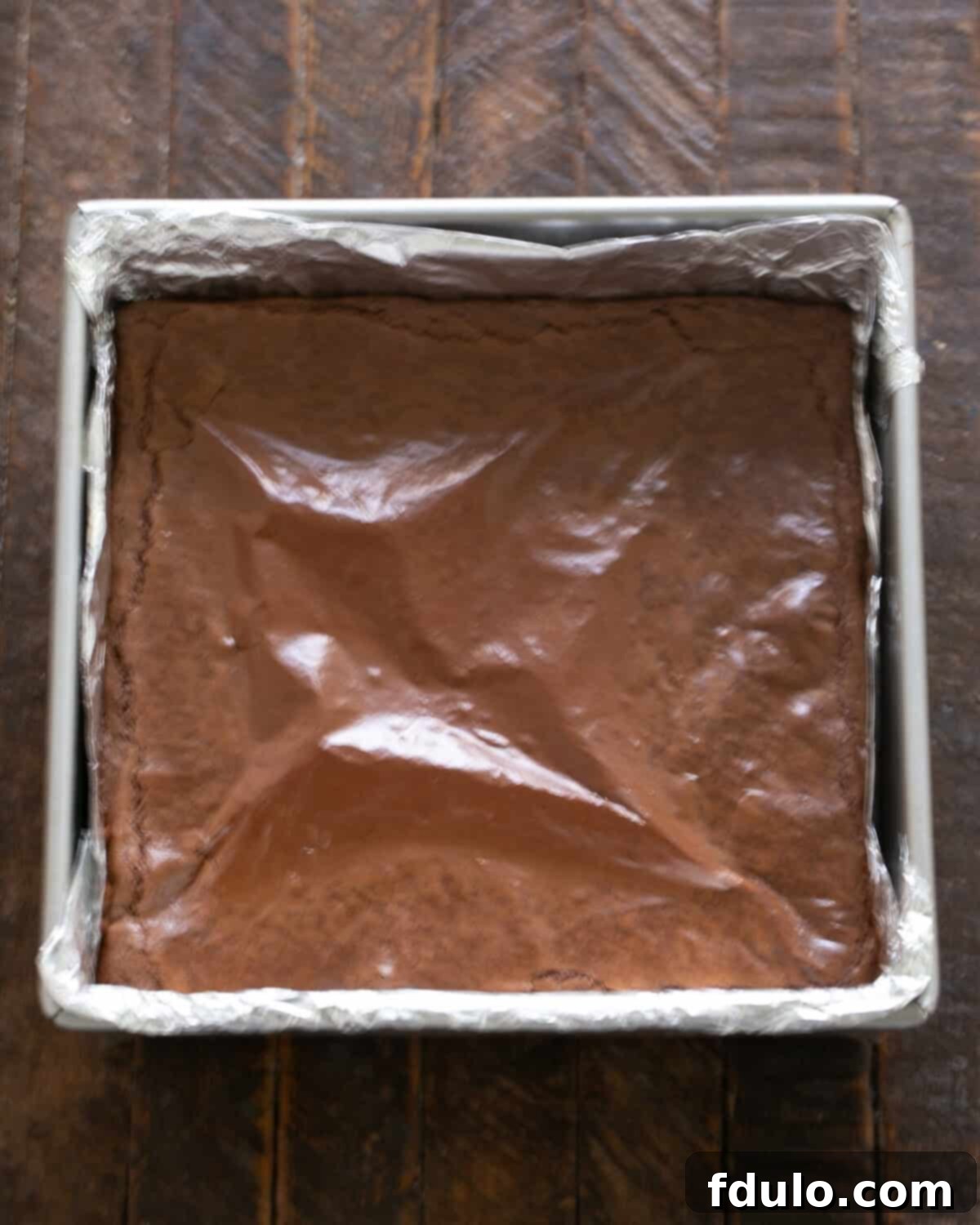 Step-by-step image depicting cooled brownies being removed from the pan using the foil liner, then sliced into perfect squares.