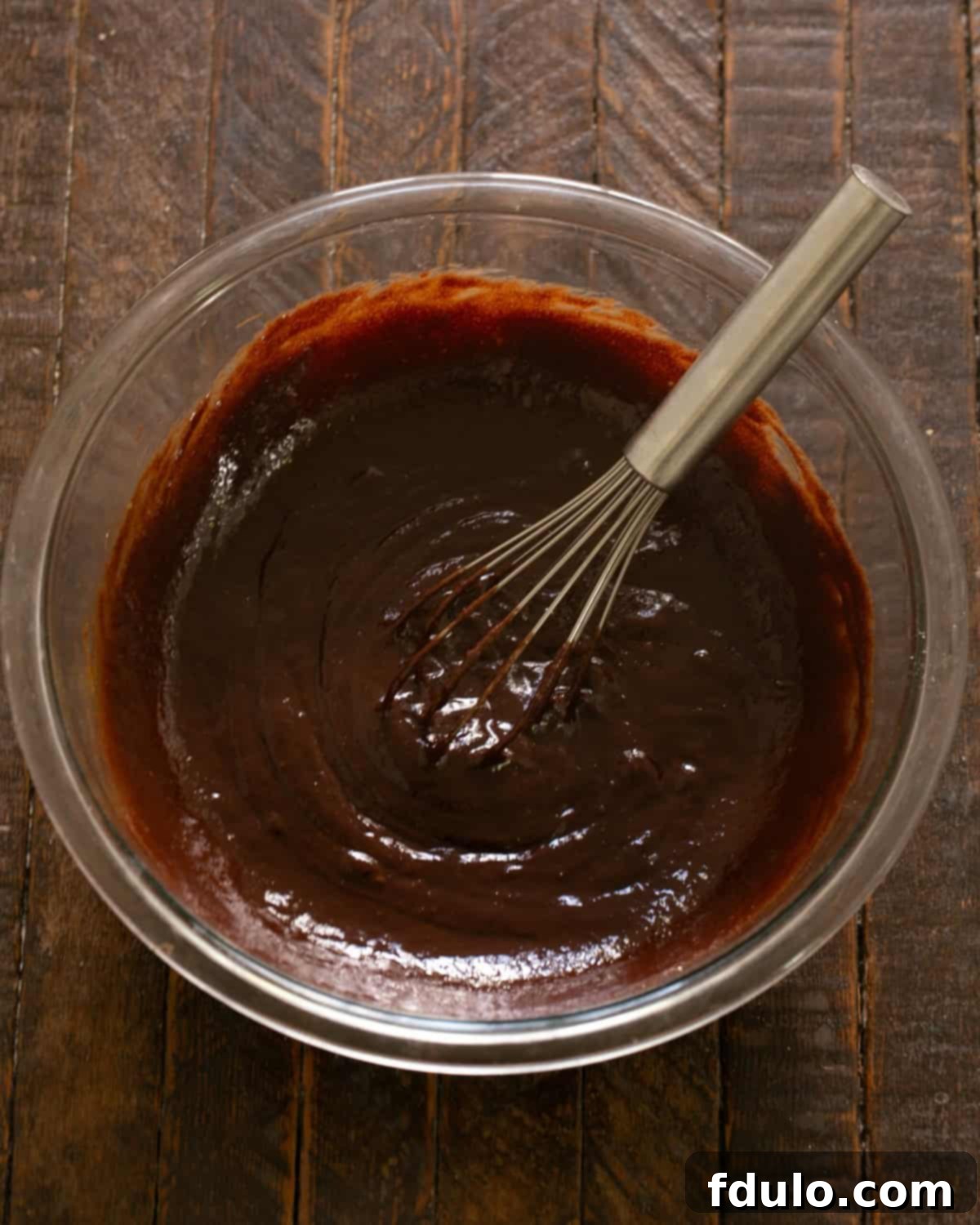 Step-by-step image demonstrating how to beat eggs into the brownie batter one at a time.