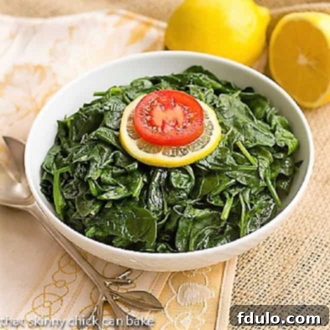 Freshly steamed baby spinach with lemon zest served in an elegant white bowl, ready to be enjoyed.