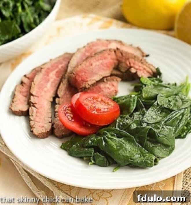 A vibrant plate featuring lemon-steamed spinach alongside juicy, ripe cherry tomatoes, offering a refreshing side dish.
