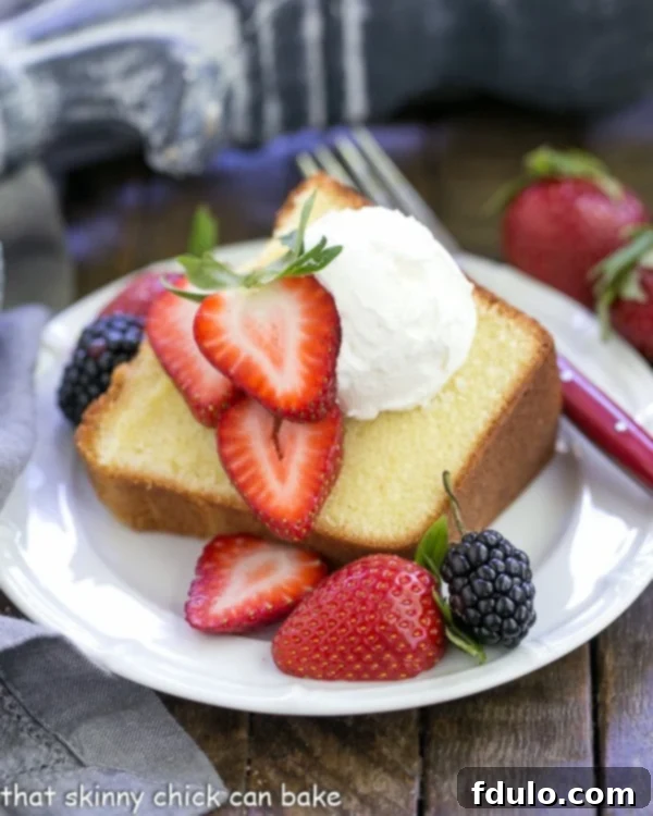 A perfectly sliced Best Pound Cake, adorned with fresh berries and a dollop of whipped cream, inviting indulgence.