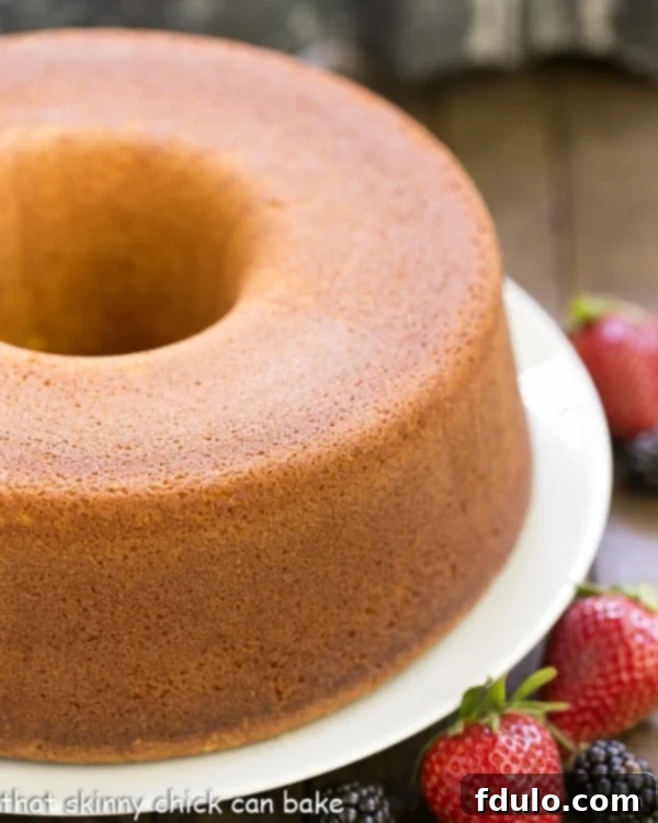 A pristine, golden-brown pound cake resting on a pristine white cake plate, ready to be sliced and enjoyed.