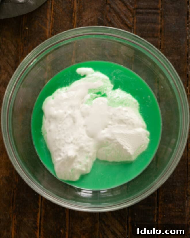 Step 2: Marshmallow creme being added to a bowl containing milk and creme de menthe.