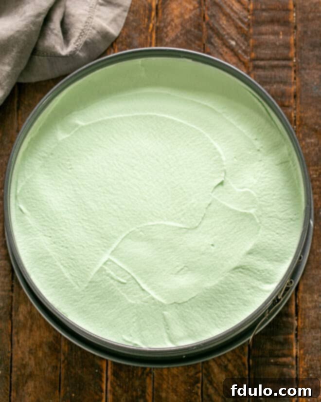 Step 4: The prepared mint filling being poured over the Oreo crust in a springform pan, ready for freezing.