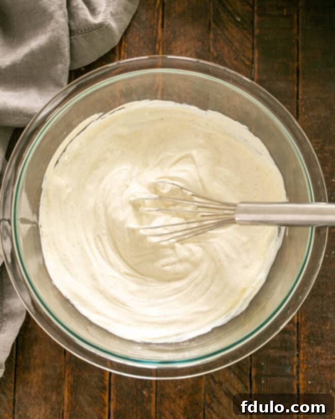 Tangy Corn Delight Dip 3 Step 1: Whisking mayonnaise and sour cream in a mixing bowl.