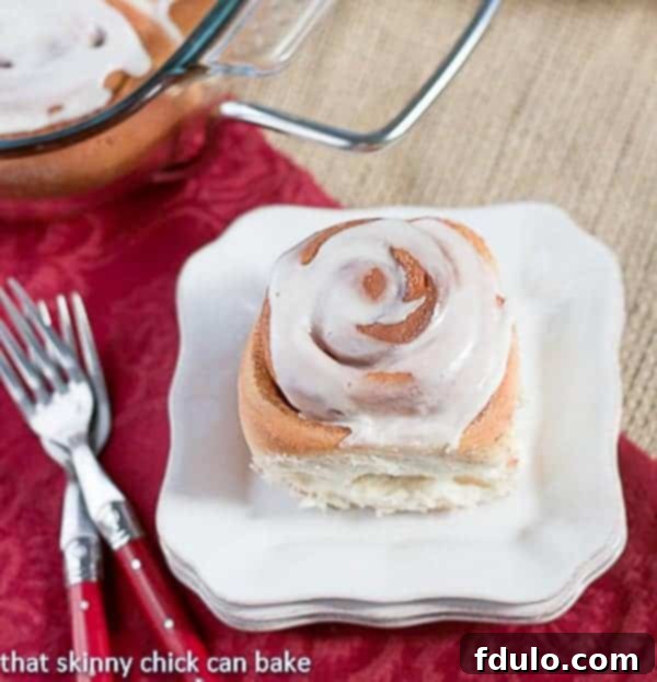 Moomie's Cinnamon Buns - Tender, old-fashioned frosted cinnamon roll on a stack of white plates!