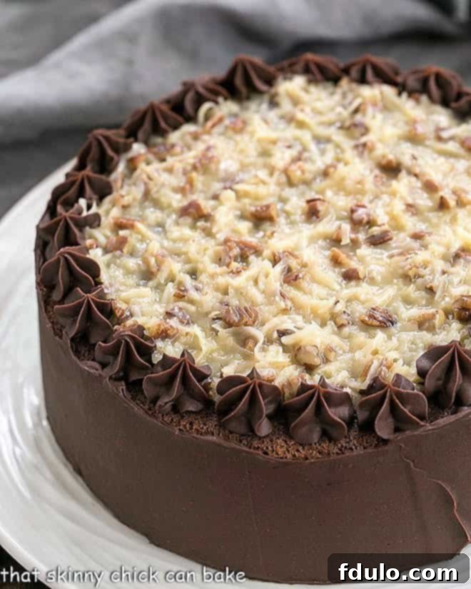 A stunning Homemade German Chocolate Cake on a white cake plate, showcasing its beautiful layers and rich filling, ready to be served.