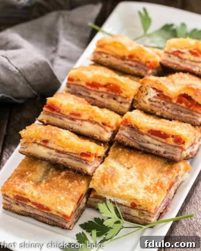Antipasto Squares lined up on a rectangular platter, showcasing their golden crust and filling.