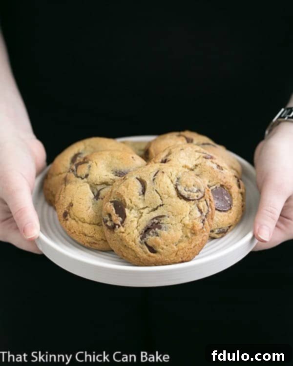 Jacques Torres' Secret Chocolate Chip Cookies on a white plate held by a girl's hands, emphasizing their generous size.