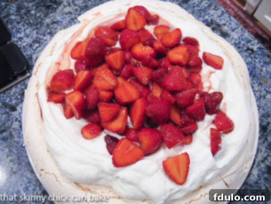 An overhead view of a fresh Strawberry Pavlova artfully arranged on a kitchen counter, showcasing the beautiful presentation of this dessert.