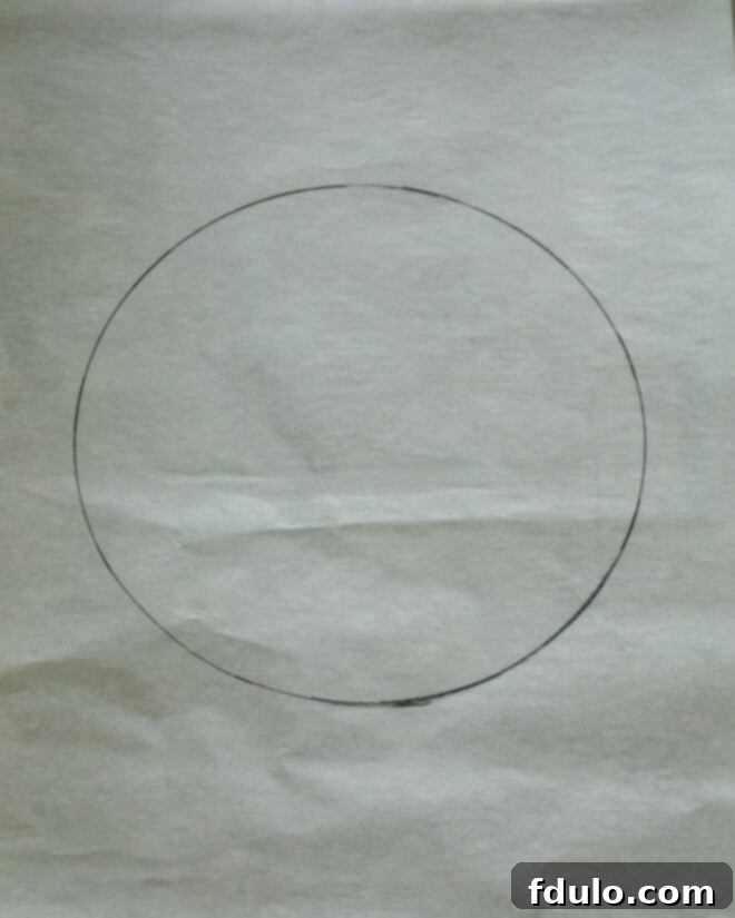 A piece of parchment paper on a baking sheet with an 8 or 9-inch circle traced on it, serving as a guide for the pavlova meringue.