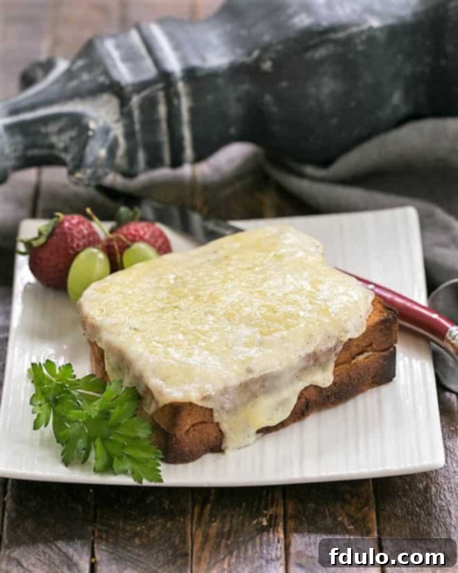 A beautifully presented Croque Monsieur on a white plate, served with a red-handled knife, showcasing its crispy top and inviting golden color.