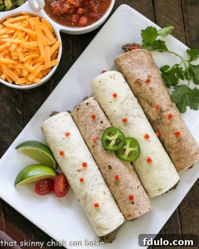 Overhead view of 4 soft shell beef tacos on a white platter with peppers and cilantro to garnish, highlighting their delicious appeal.