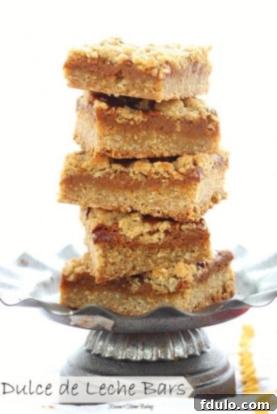 Stack of freshly baked Dulce de Leche Bars on a metal serving dish, showcasing their gooey center.