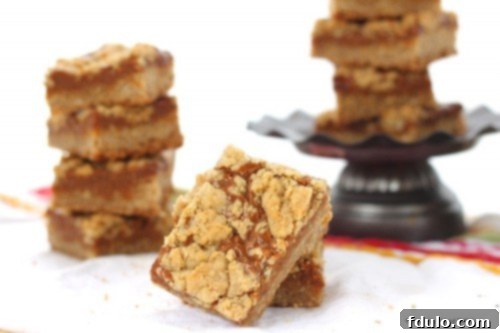 Close-up of three Dulce de Leche Bars stacked on a small white pedestal, showing the thick caramel layer.