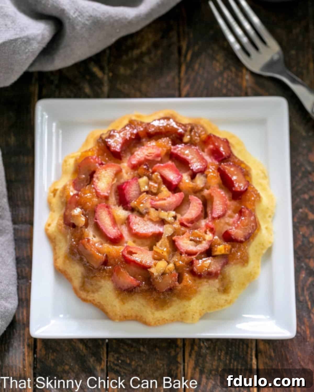 Raventli Tepetaklak Kekçikler 3 A single Fresh Rhubarb Upside-down Baby Cake on a square white plate, showing the caramelized rhubarb and pecans.