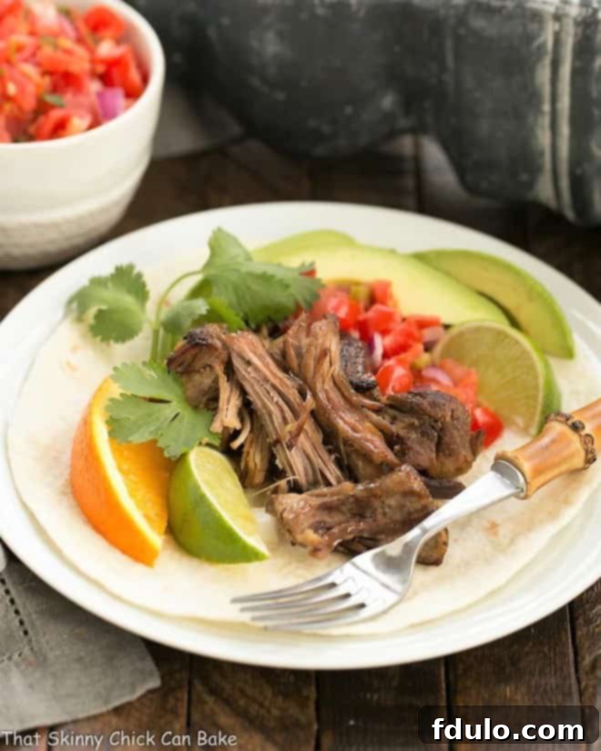 Slow cooked Pork Carnitas on a white plate with a bamboo fork.