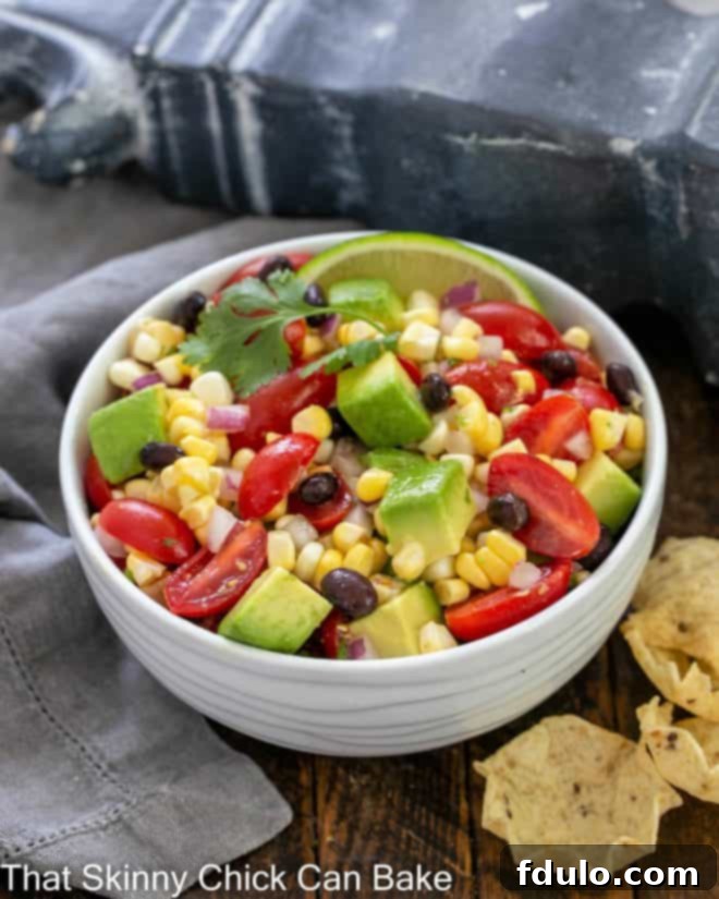 Corn salsa recipe in a white ceramic serving bowl with a cilantro garnish