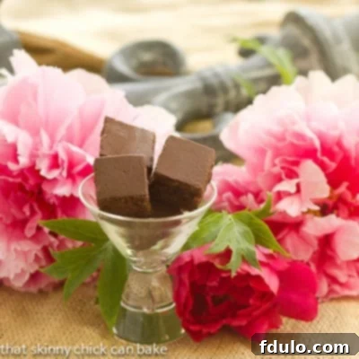 Rich and fudgy Refrigerator Brownies in a martini glass, surrounded by elegant pink peonies