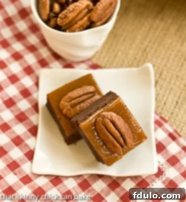 Two exquisite Turtle Brownies resting on a square white plate, set against a charming red and white checkered napkin.