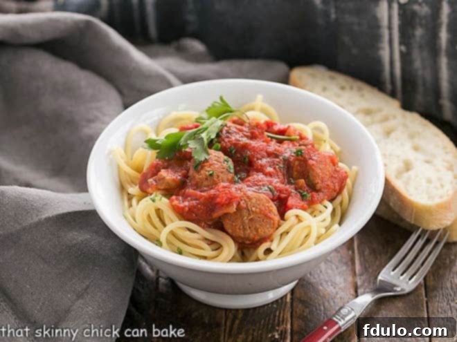 Pasta Sauce Recipe with Sausage in a white bowl with a red handled fork