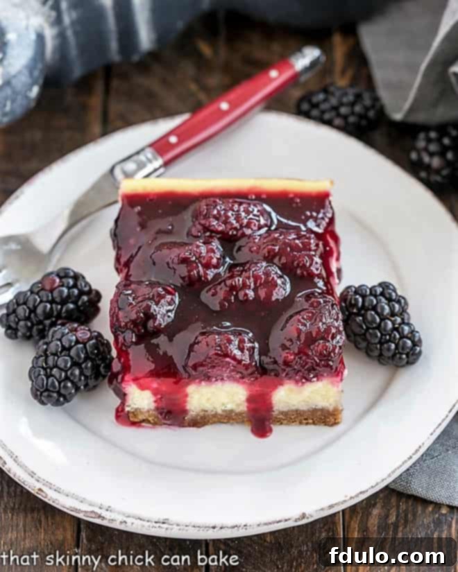 Blackberry Cheesecake Bars on a round white plate with fresh blackberries and a red handled fork.