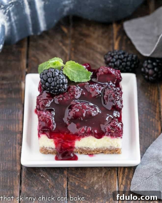 Cheesecake Bar with Berry Topping on a square white plate with a sprig of mint.