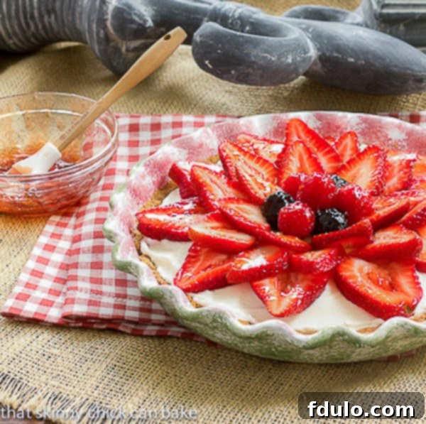 Close-up of Strawberry Cream Cheese Dessert being glazed, showing a bowl of jelly and a brush.