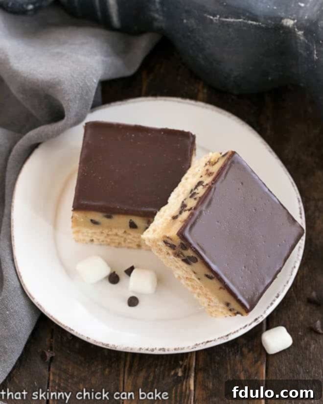 Overhead view of a single Cookie Dough Rice Krispie Treat on a round white plate, showcasing its distinct layers of crispy cereal, creamy cookie dough, and glossy chocolate ganache.