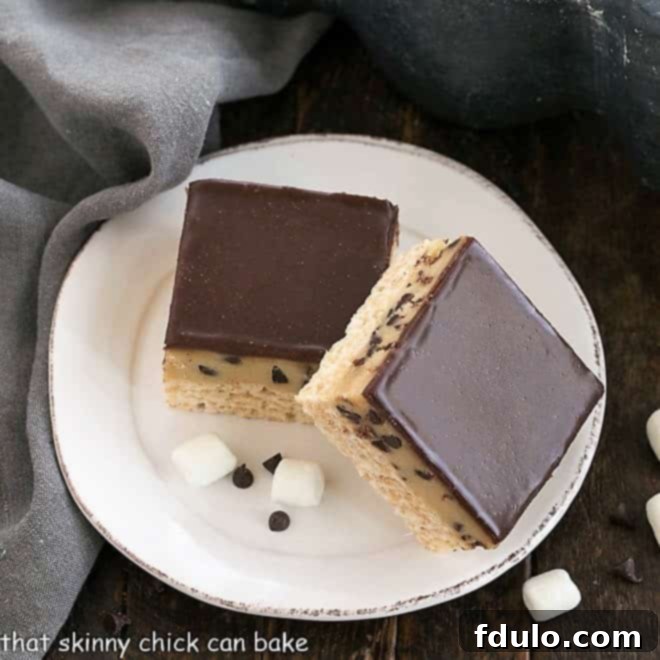 Two cookie dough rice krispie bars on a white plate, ready to be enjoyed.