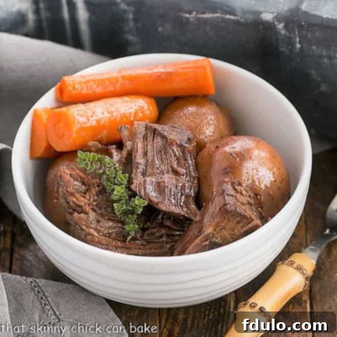 Instant Pot Beef Stew in a round white bowl with carrots and a sprig of thyme