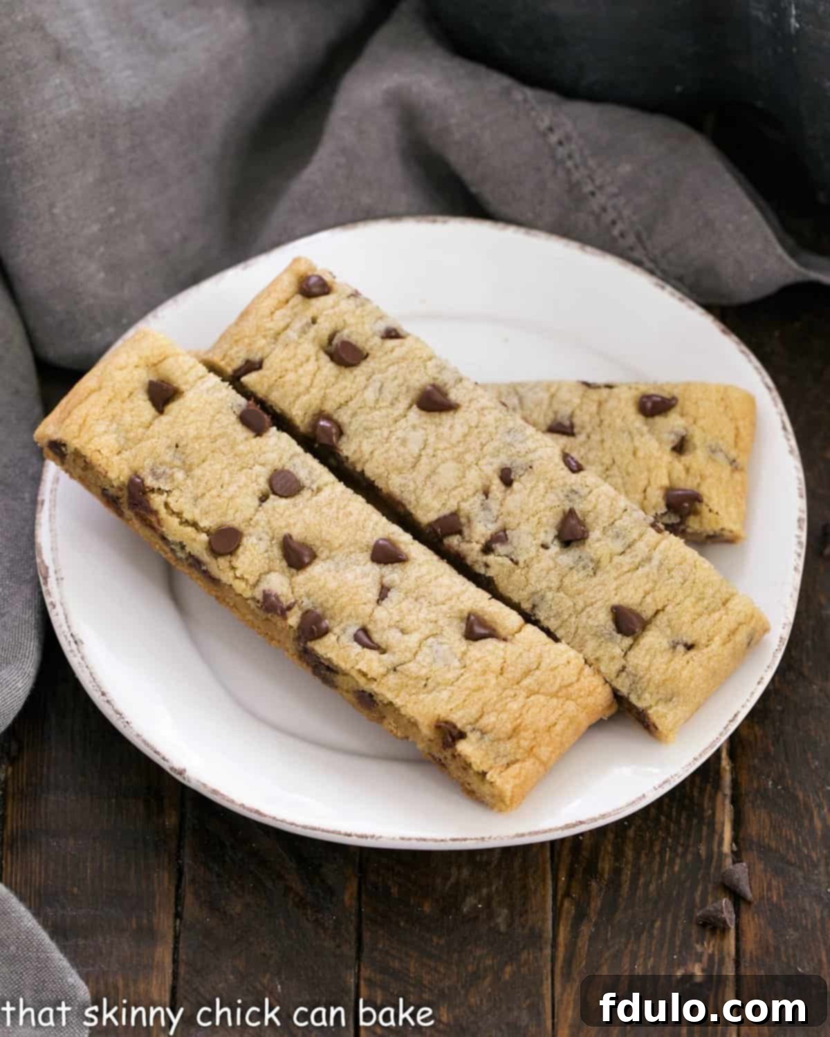 Several golden-brown chocolate chip cookie dippers, artfully arranged on a small white ceramic plate, ready for a delightful treat.