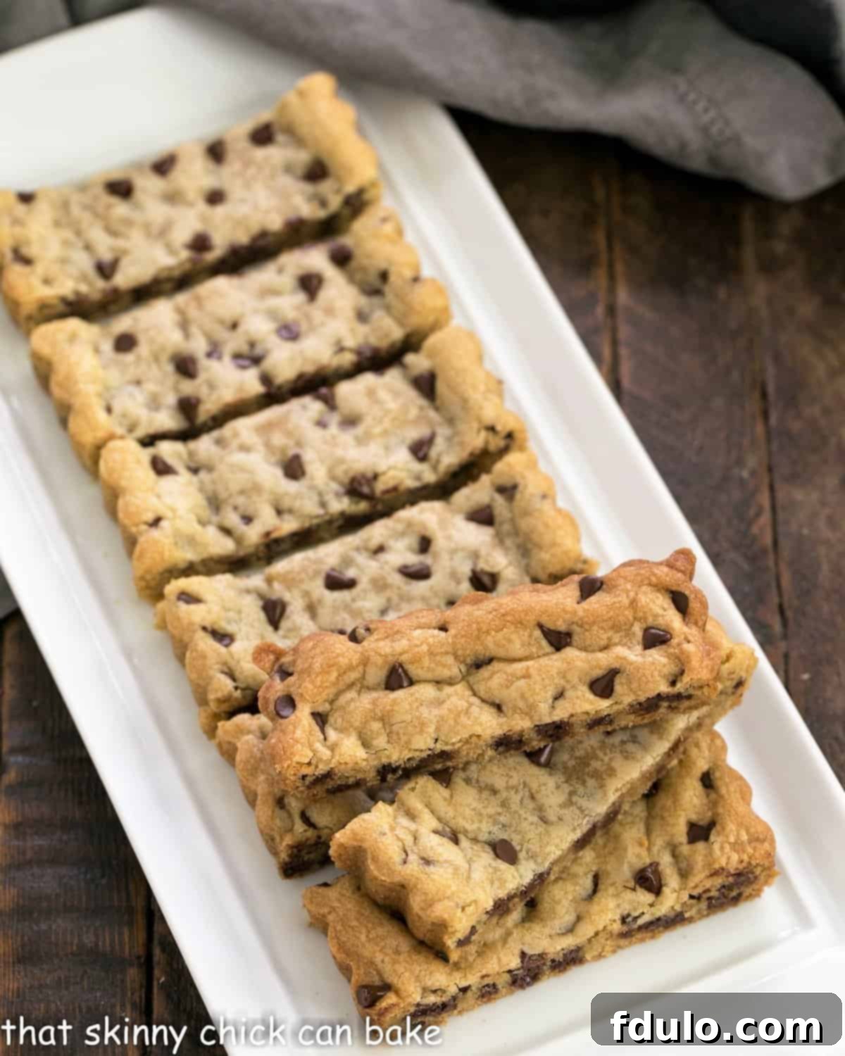 A tray filled with freshly baked chocolate chip cookie bars, golden-brown and studded with chocolate, ready to be sliced into sticks.