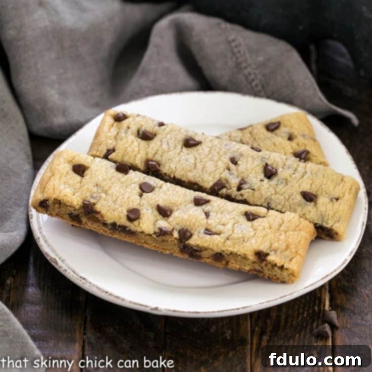 Three golden-brown chocolate chip cookie sticks on a small white plate, perfectly presented for tasting.