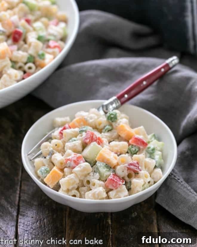 Easy pasta salad recipe in a small white bowl with a red handled fork, ready to be eaten.