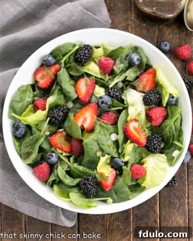Overhead view of a beautifully arranged Spinach Almond and Berries Salad in a white bowl, ready to serve.