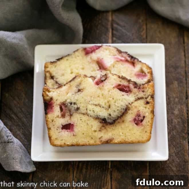 Two enticing slices of homemade Rhubarb Bread, featuring the prominent cinnamon swirl, elegantly presented on a square white plate.