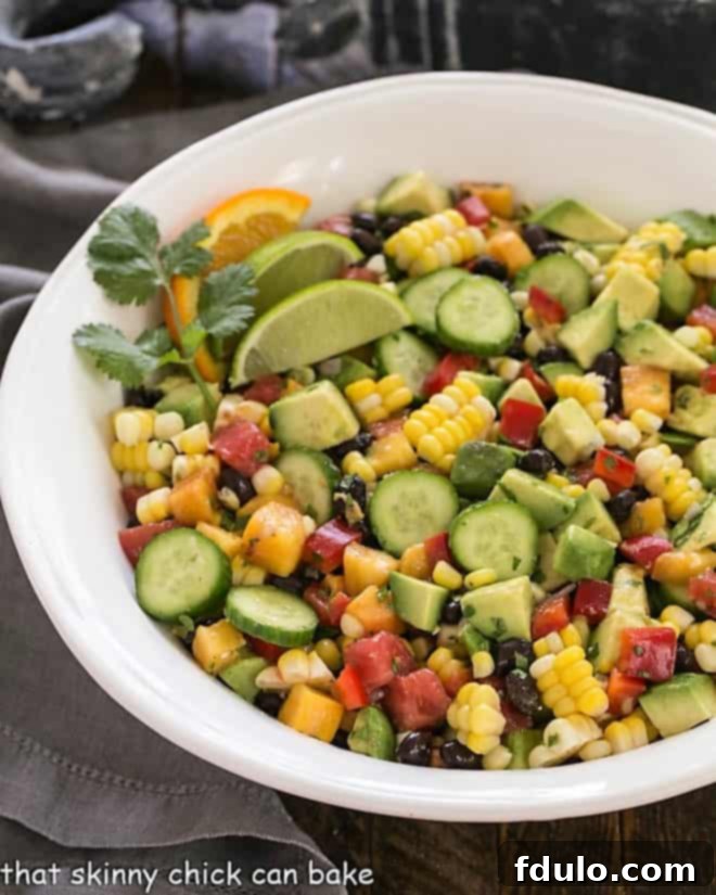 This Southwest Chopped Salad is chock full of delicious summer produce and dressed in a light, flavorful cilantro lime vinaigrette! Overhead view of a beautifully arranged Southwest chopped salad in a large white serving bowl, showcasing vibrant colors and fresh ingredients like corn, black beans, tomatoes, and avocado.