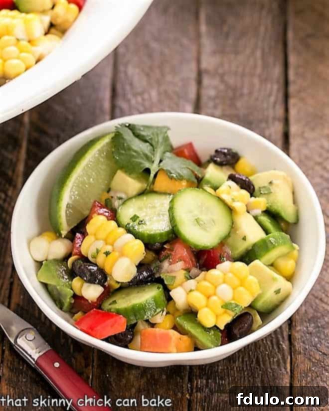 This Southwest Summer Salad is chock full of delicious summer produce and dressed in a light, flavorful cilantro lime vinaigrette! A small white bowl showcasing a portion of the colorful black bean and corn salad, highlighting its fresh appeal and delicious texture.