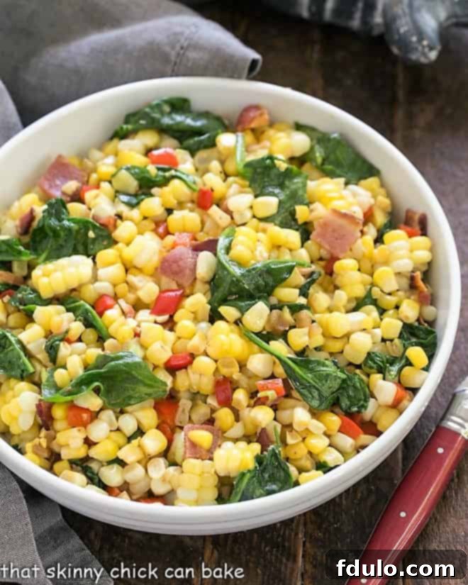 Skillet Corn with Spinach and Peppers - a deliciously flavorful side dish made with fresh or defrosted frozen corn, bacon and more! Overhead view of Skillet Corn with Spinach and Peppers served in a white bowl, garnished with fresh herbs.