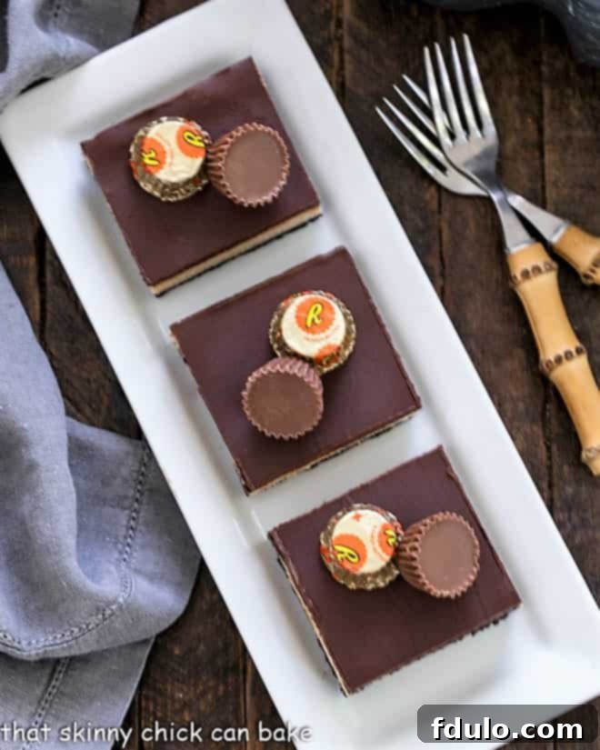 Overhead view of 3 cheesecake bars on a rectangular white tray, garnished with mini peanut butter cups.