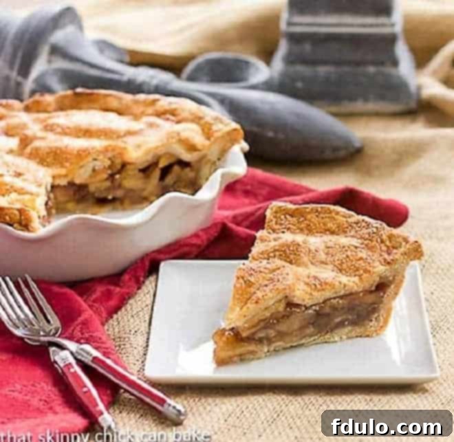 Classic Apple Pie - Sweet, cinnamon spiced apples in a flaky pastry crust A delectable slice of Classic Apple Pie, showcasing its golden, flaky crust and cinnamon-spiced apple filling, served on a square white plate, ready to be enjoyed.