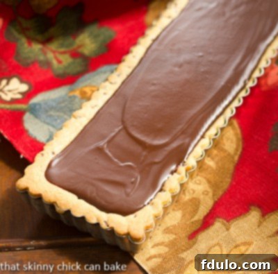 Chocolate Chip Cookie Tart with Caramel and Chocolate Glaze displayed in a rectangular tart pan, ready to be sliced
