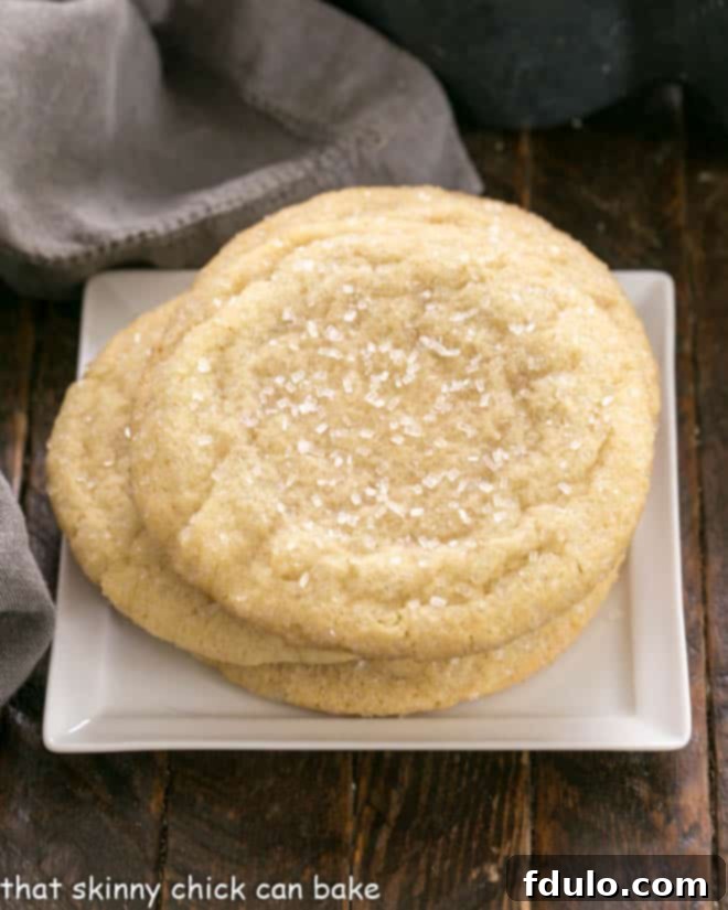Overhead view of a stack of Big Homemade Sugar Cookies on a square white plate, glistening with sugar.