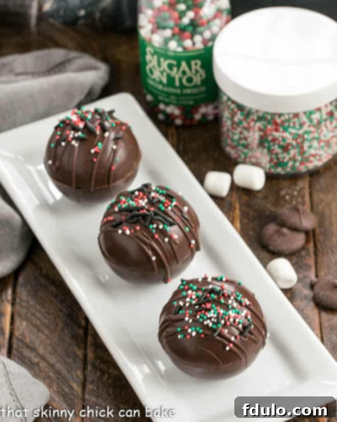 3 hot chocolate bombs on a white tray, glistening under soft light.